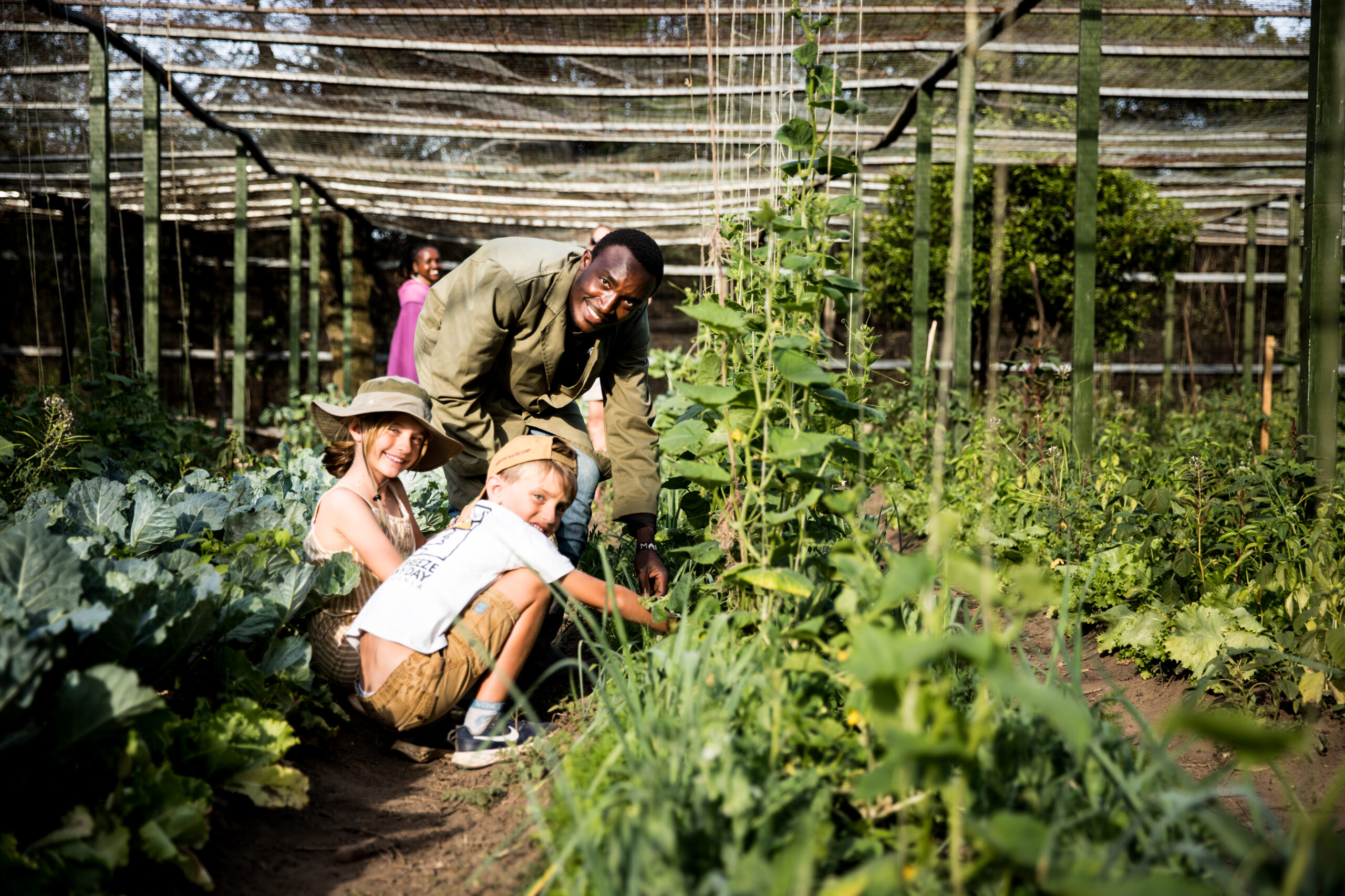 A parent and a child at one of the best Kenya family safari camps for families, picking out crops with local tour guide